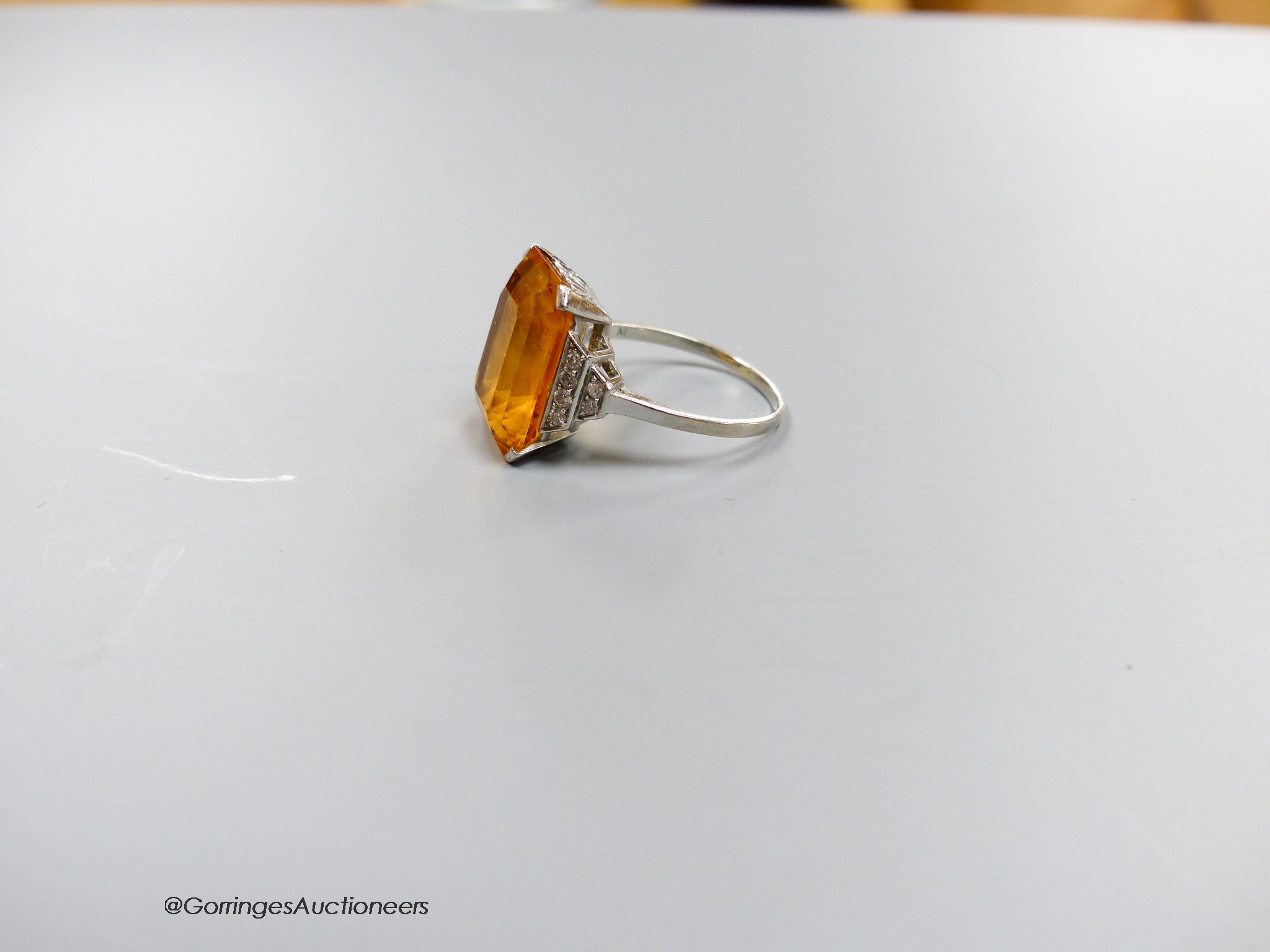 A white metal and emerald cut yellow topaz set dress ring, with diamond set shoulders, size N, gross weight 6.5 grams.